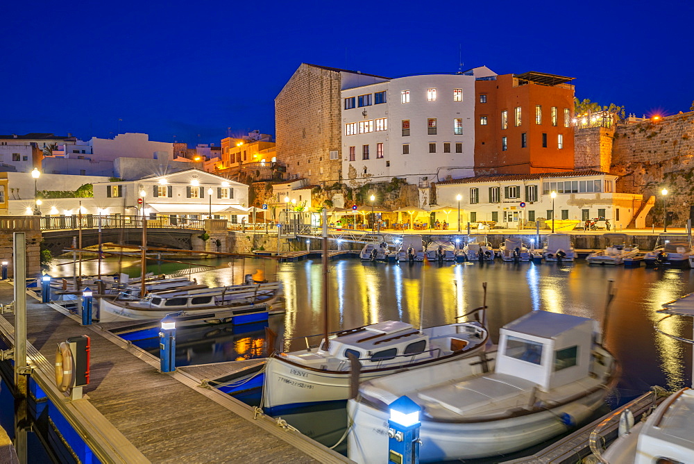 View of boats in marina overlooked by whitewashed buildings at dusk, Ciutadella, Menorca, Balearic Islands, Spain, Mediterranean, Europe