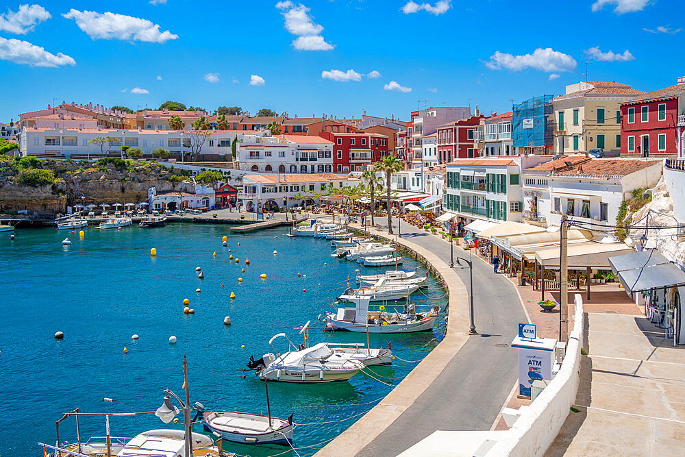 View of colourful cafes, restaurants and boats in harbour against blue sky, Cales Fonts, Menorca, Balearic Islands, Spain, Mediterranean, Europe