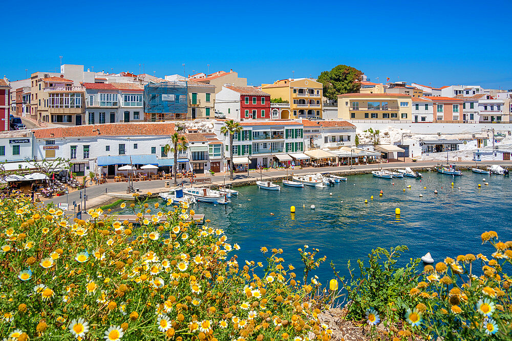 View of colourful cafes, restaurants and boats in harbour against blue sky, Cales Fonts, Menorca, Balearic Islands, Spain, Mediterranean, Europe