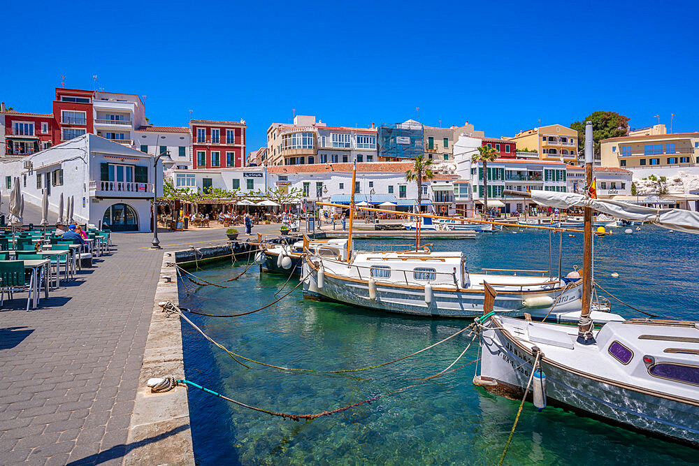 View of colourful cafes, restaurants and boats in harbour against blue sky, Cales Fonts, Menorca, Balearic Islands, Spain, Mediterranean, Europe