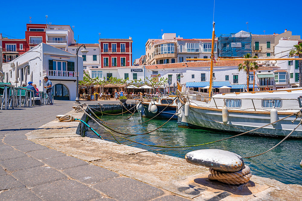 View of colourful cafes, restaurants and boats in harbour against blue sky, Cales Fonts, Menorca, Balearic Islands, Spain, Mediterranean, Europe