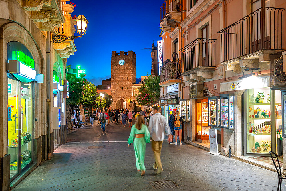 View of Torre dell'Orologio e Porta di Mezzo and busy street in Taormina at dusk, Taormina, Sicily, Italy, Mediterranean, Europe