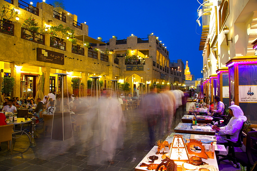 Souq Waqif looking towards the illuminated spiral mosque of the Kassem Darwish Fakhroo Islamic Centre, Doha, Qatar, Middle East