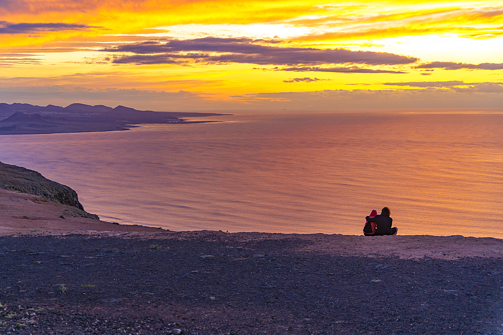 View of couple overlooking volcanic coastline from Mirador del Rio at sunset, Lanzarote, Las Palmas, Canary Islands, Spain, Atlantic, Europe