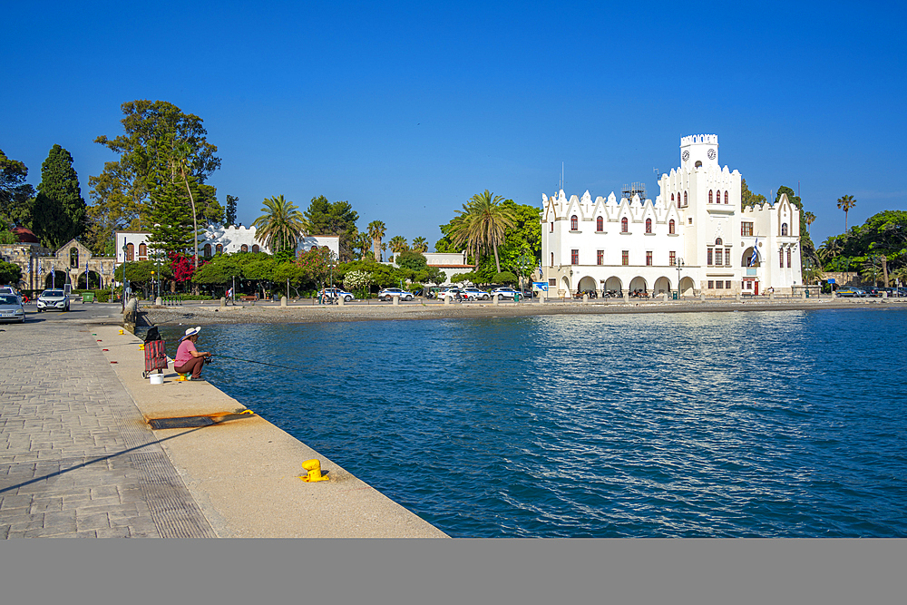 View of man fishing and County Government Office, Kos Town, Kos, Dodecanese, Greek Islands, Greece, Europe