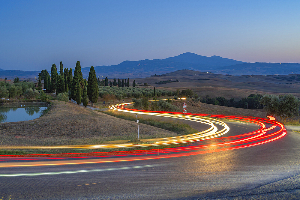 View of car trail lights in Tuscan landscape near Pienza at dusk, Pienza, Province of Siena, Tuscany, Italy, Europe