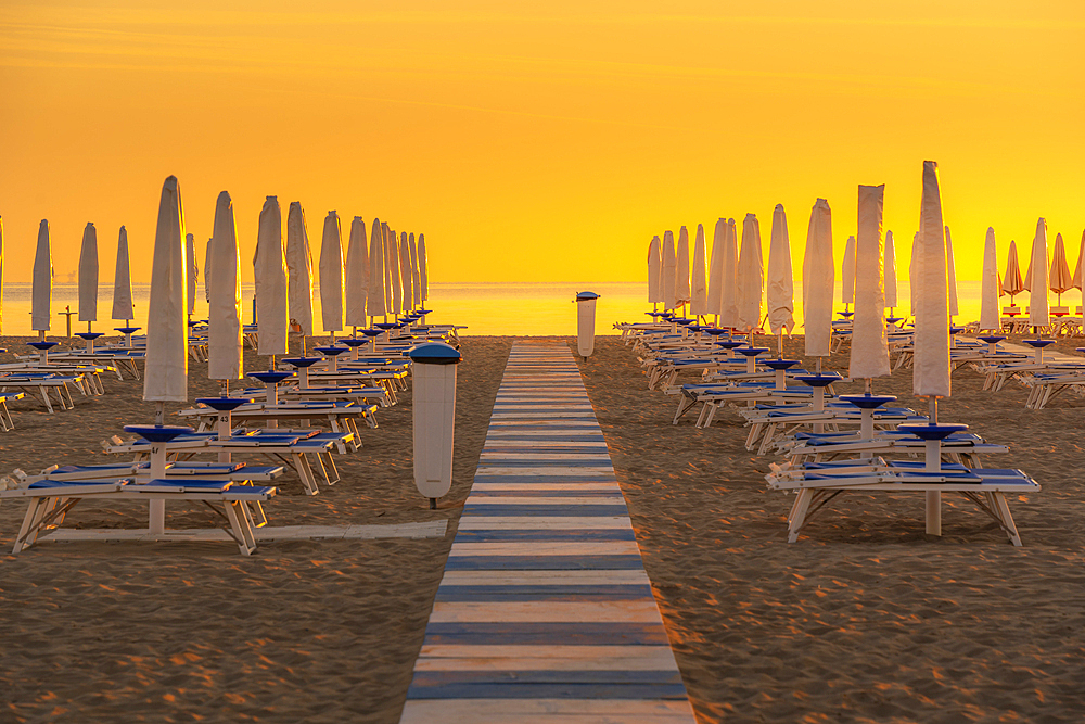 View of sunrise and sunshades on the Lido on Rimini Beach, Rimini, Emilia-Romagna, Italy, Europe