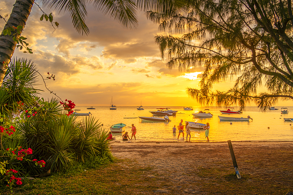 View of boats and people on Mon Choisy Public Beach at sunset, Mauritius, Indian Ocean, Africa