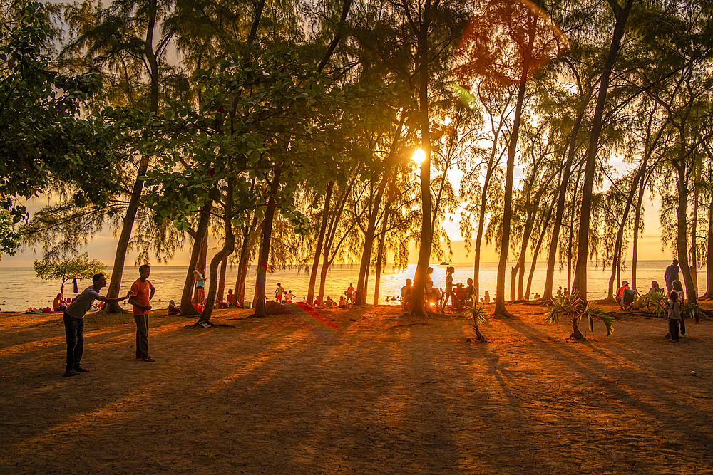 View of trees and people on Mon Choisy Public Beach at sunset, Mauritius, Indian Ocean, Africa