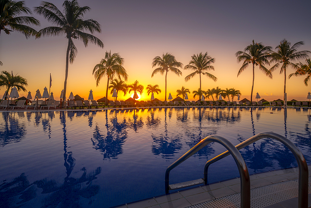 View of sunrise and palm tree reflections in hotel pool near Puerto Morelos, Caribbean Coast, Yucatan Peninsula, Mexico, North America