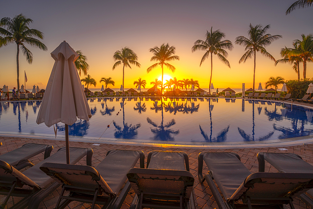 View of sunrise and palm tree reflections in hotel pool near Puerto Morelos, Caribbean Coast, Yucatan Peninsula, Mexico, North America