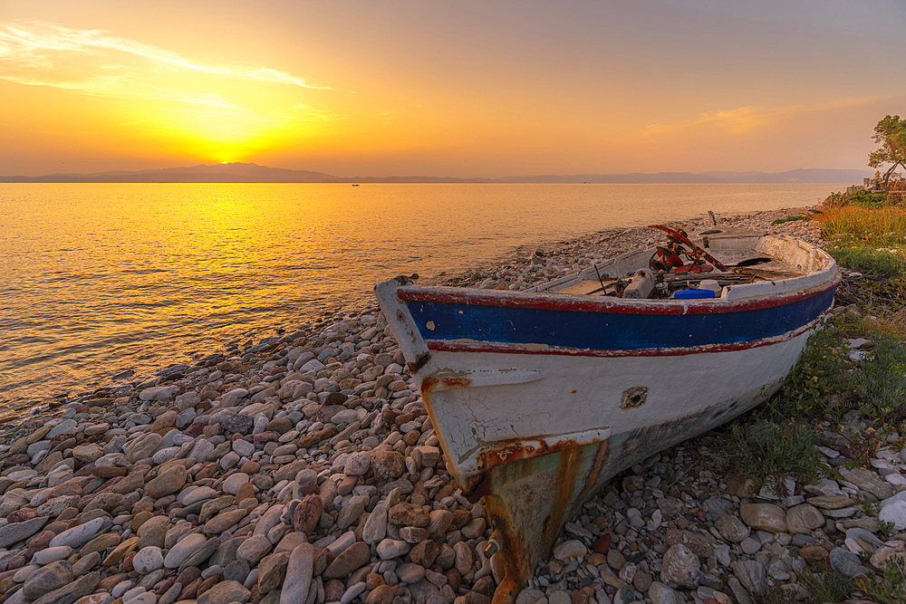 View of boat on pebble beach near Skala Kallirachis at sunset, Skala Kallirachis, Thassos, Aegean Sea, Greek Islands, Greece, Europe