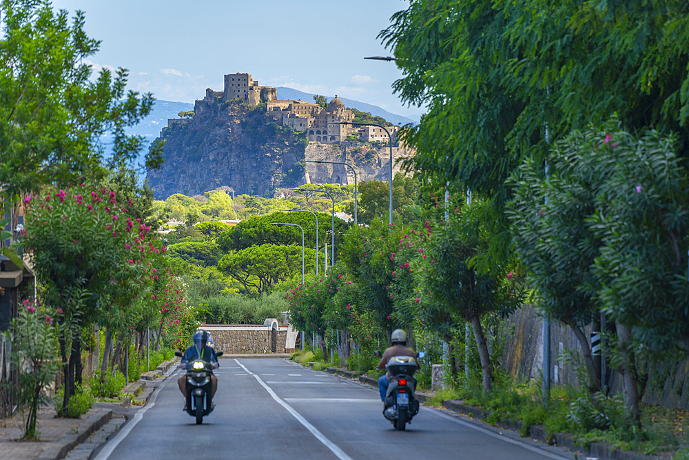 View of scooter riders and Castello Aragonese d'Ischia from Porto d'Ischia (Port of Ischia), Island of Ischia, Campania, Italy, Europe