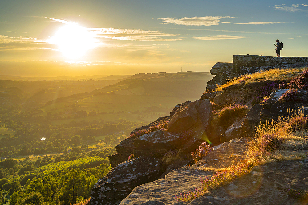 View of hiker viewing landsacpe from Curbar Edge at sunset, Peak District National Park, Baslow, Derbyshire, England, United Kingdom, Europe