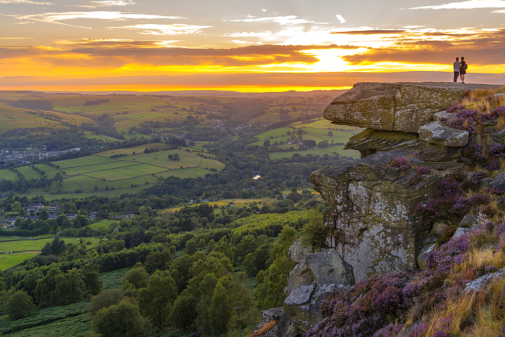 View of man and woman viewing landscape from Curbar Edge at sunset, Peak District National Park, Baslow, Derbyshire, England, United Kingdom, Europe