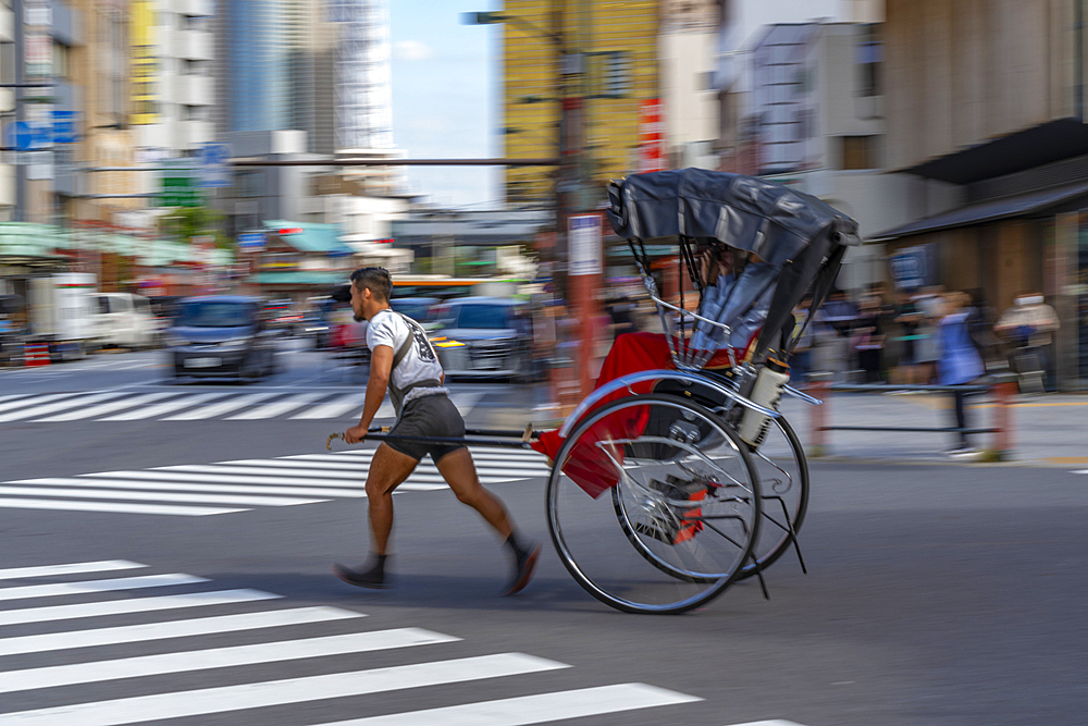 View of Japanese rickshaw (jinrikisha) in busy street scene, Asakusa, Taito City, Tokyo, Honshu, Japan