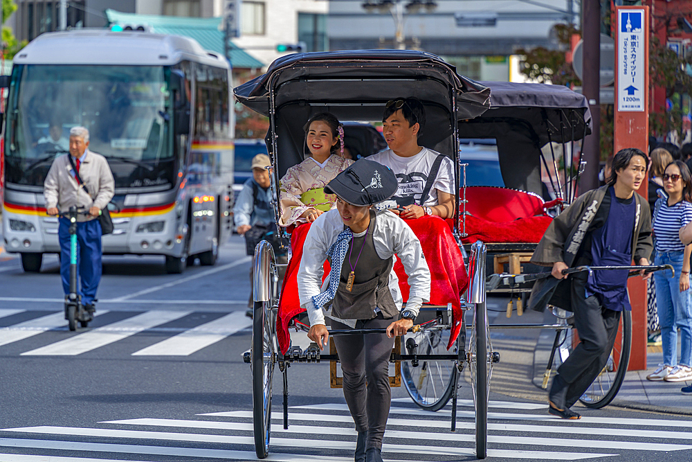 View of Japanese rickshaw (jinrikisha) in busy street scene, Asakusa, Taito City, Tokyo, Honshu, Japan