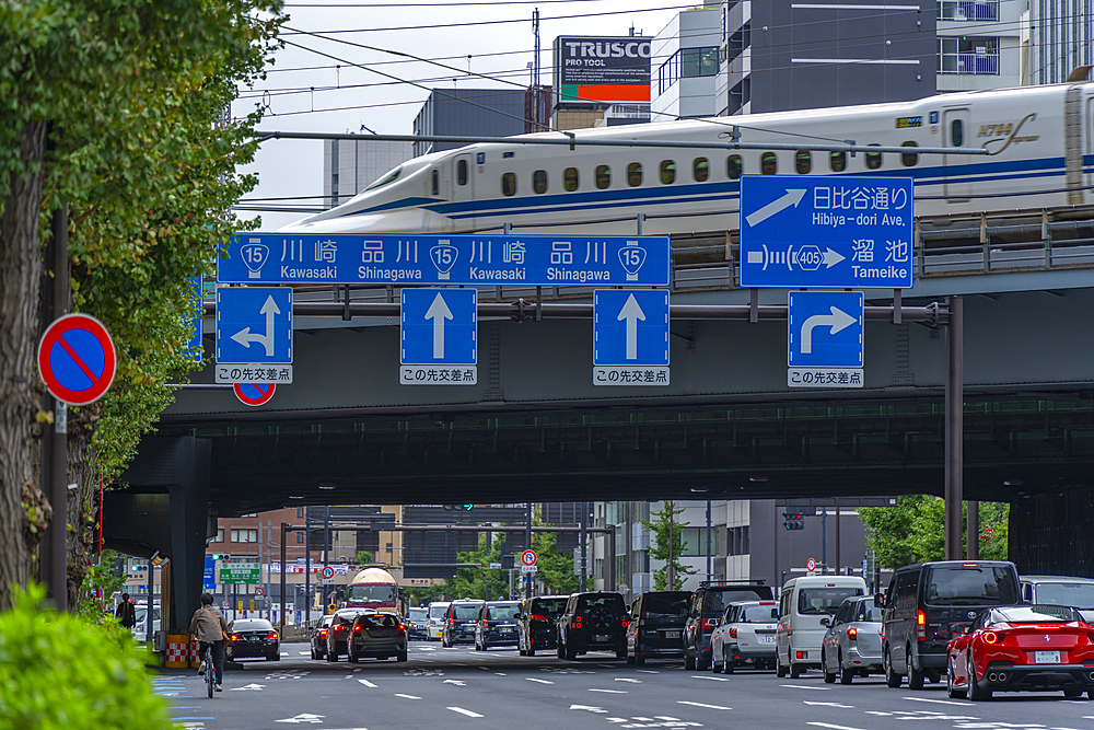 View of bullet train passing over bridge with city traffic, Minato City, Tokyo, Honshu, Japan