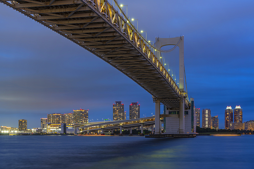 View of the Rainbow Bridge and Koto City in background at dusk, Minato City, Tokyo, Honshu, Japan