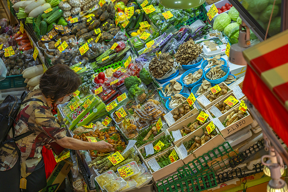 Elevated view of woman inspecting colourful fresh vegetables on stall in Omicho Market, Kanazawa City, Ishikawa Prefecture, Honshu, Japan