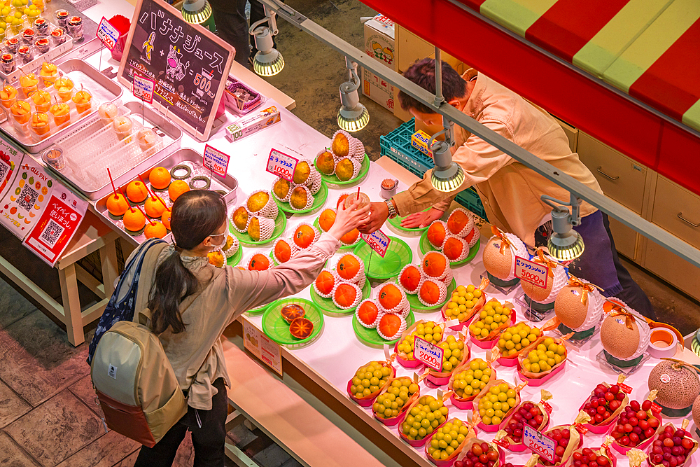 Elevated view of customer being served at colourful fresh fruit stall in Omicho Market, Kanazawa City, Ishikawa Prefecture, Honshu, Japan, Asia