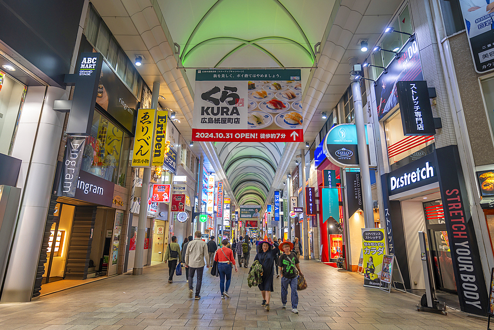 View of colourful shops and restaurants in shopping arcade at night, Hiroshima, Honshu, Japan