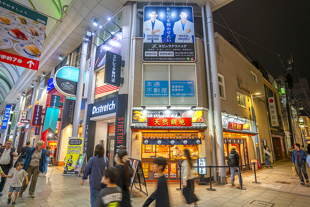 View of colourful shops and restaurants in shopping arcade at night, Hiroshima, Honshu, Japan