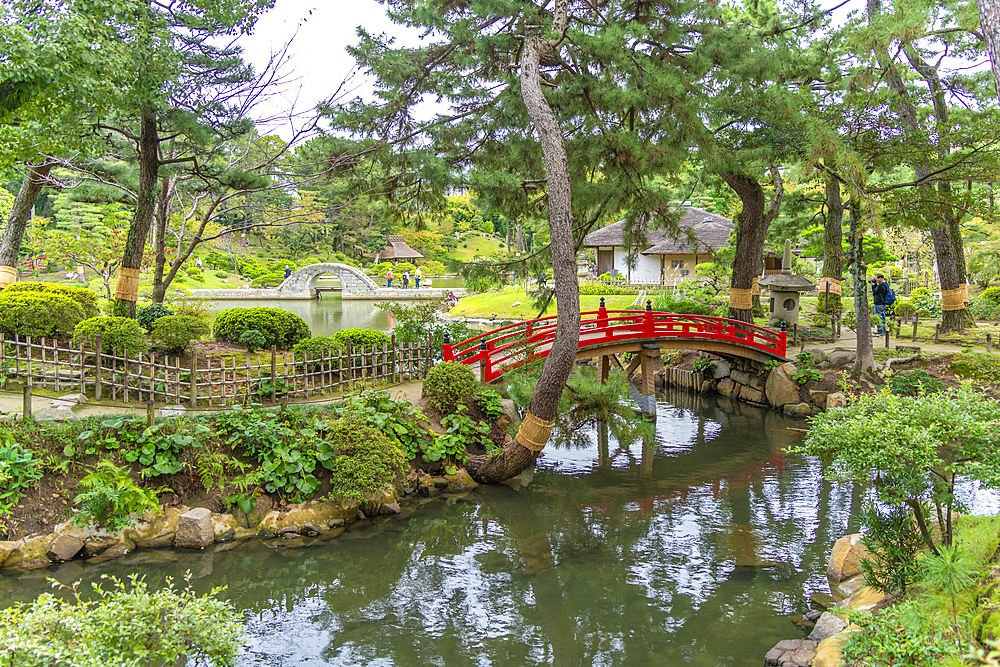 View of red footbridge over Takueichi Pond in Shukkeien Garden, Kaminoboricho, Naka Ward, Hiroshima, Japan, Asia