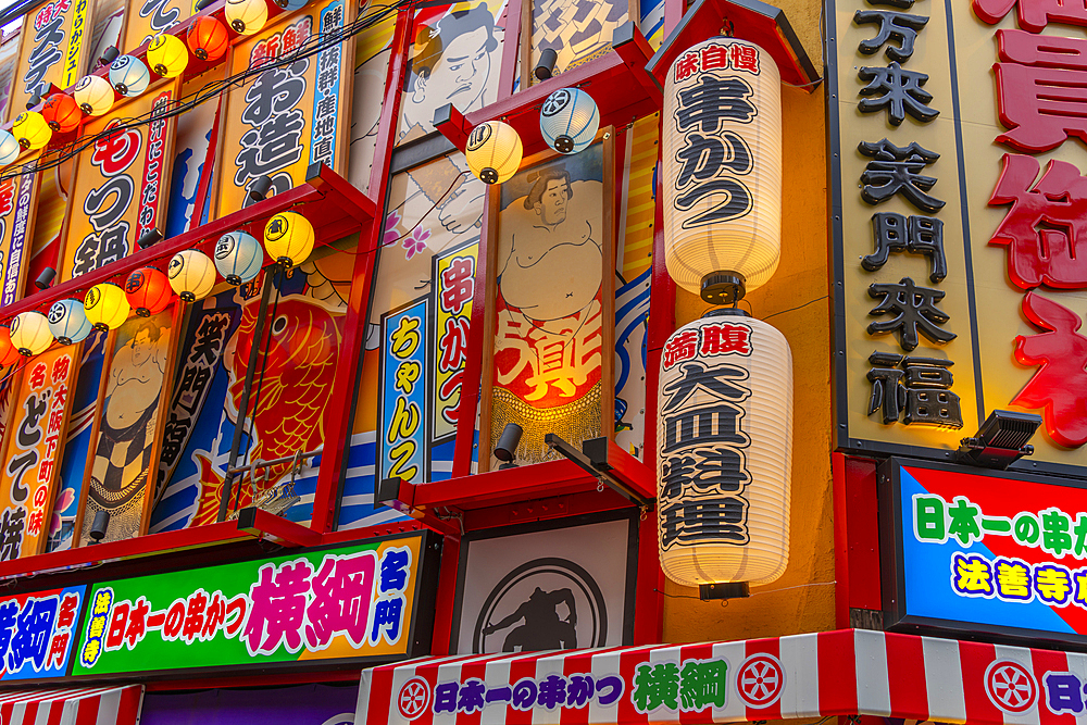 View of colourful facades of shops and restaurants in Dotonbori, vibrant entertainment district near the river, Osaka, Honshu, Japan