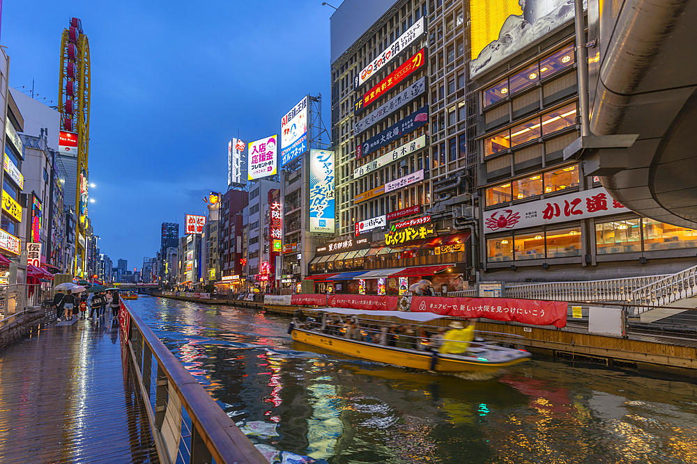 View of tour boat and colourful adverts in Dotonbori, vibrant entertainment district near the river at dusk, Osaka, Honshu, Japan