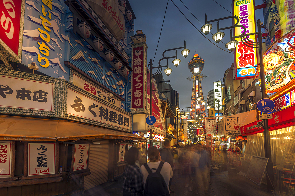 View of Tsutenkaku Tower and restaurants neon lights at night in the Shinsekai area, Osaka, Honshu, Japan