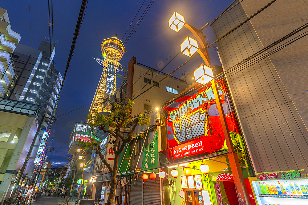 View of Tsutenkaku Tower and restaurants neon lights at dusk in the Shinsekai area, Osaka, Honshu, Japan