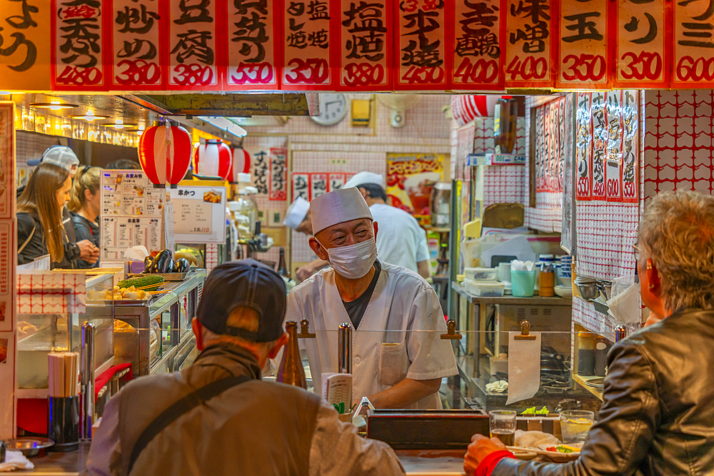 View of hot food restaurant near Tsutenkaku Tower at dusk in the Shinsekai area, Osaka, Honshu, Japan