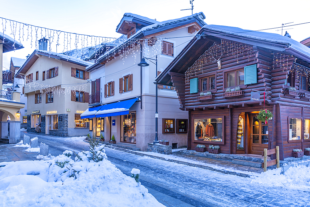 View of shops, town centre and snow covered mountains in Courmayeur at dusk during Christmas, Courmayeur, Aosta Valley, Italy, Europe