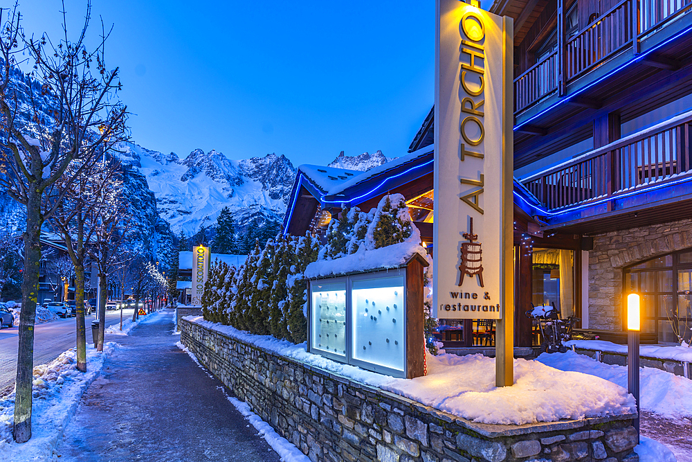 View of town centre and snow covered mountains in background at dusk, Courmayeur, Aosta Valley, Italy, Europe