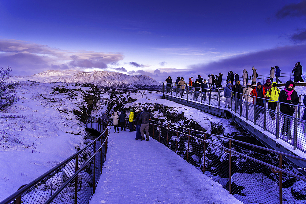 View of people and the continental drift between the North American and Eurasian tectonic plates in Thingvellir National Park during winter, Western Region, Iceland, Europe