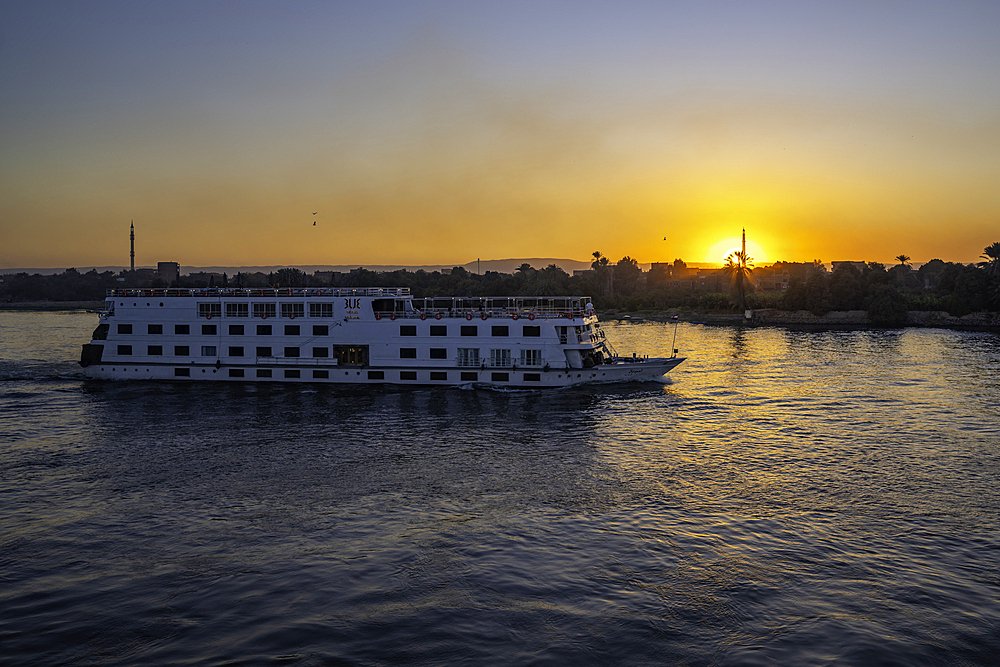 View of cruise boat and skyline from cruise boat near Esna on the Nile River at sunset, Esna, Egypt, Africa