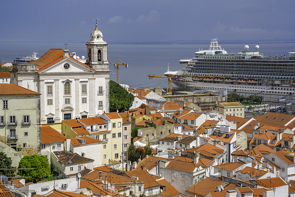 View of cruise ship in port and terrakotta rooftops in Alfama, Alfama District, Lisbon, Portugal, Europe