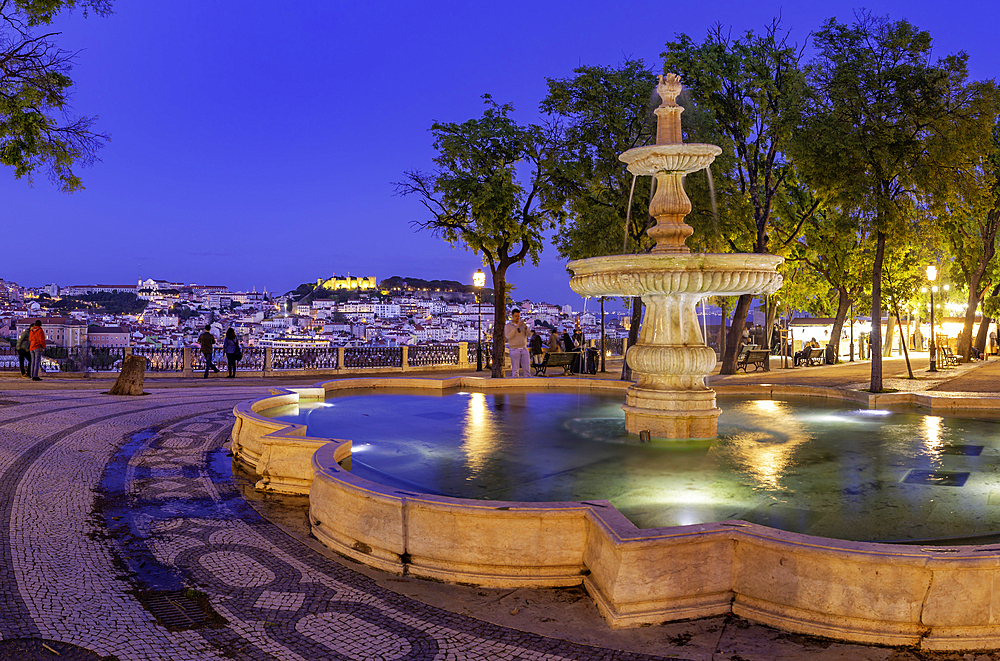 View of Lisbon and fountain in Miradouro de Sao Pedro de Alcantara at dusk, Lisbon, Portugal, Europe