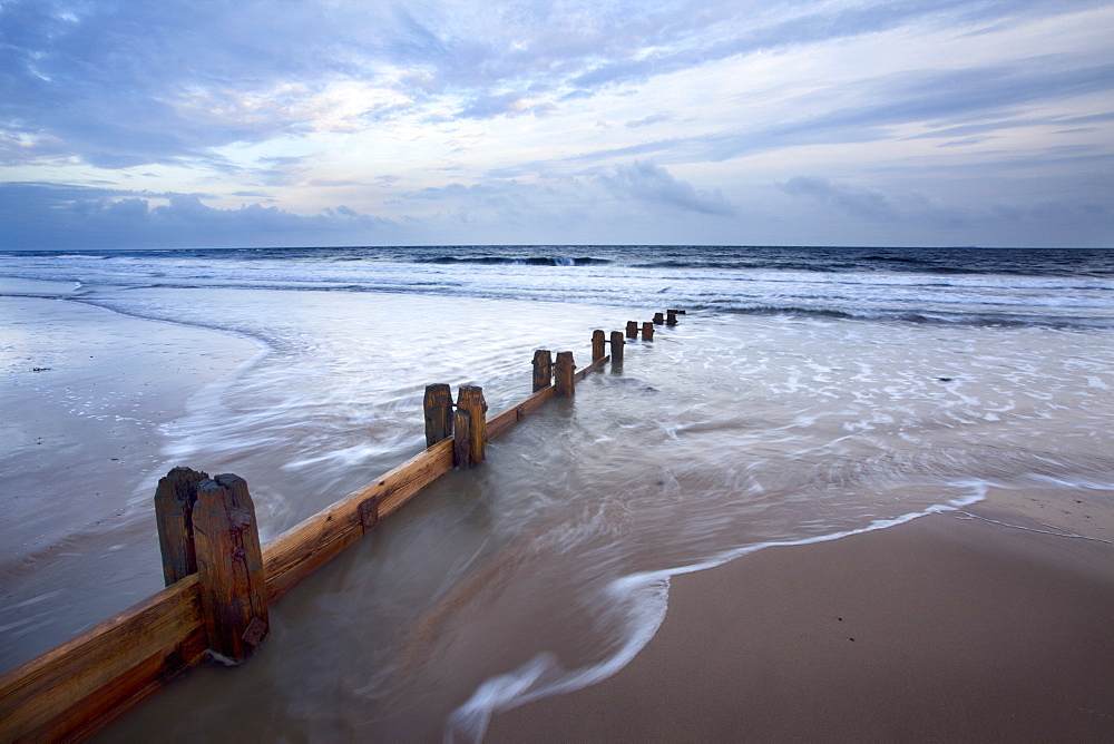 Groynes and receding tide on Alnmouth Beach at dusk, Northumberland, England, United Kingdom, Europe