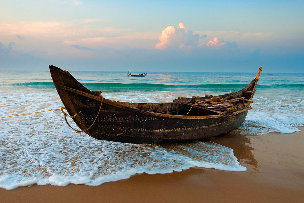 Traditional fishing boat on tide line, Chowara Beach, near Kovalam, Kerala, India, Asia