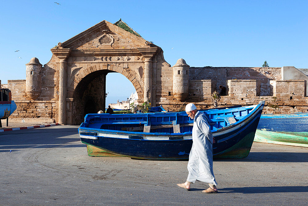 Old Muslim man walking below the old city gate and ramparts, Essaouira, Atlantic coast, Morocco, North Africa, Africa