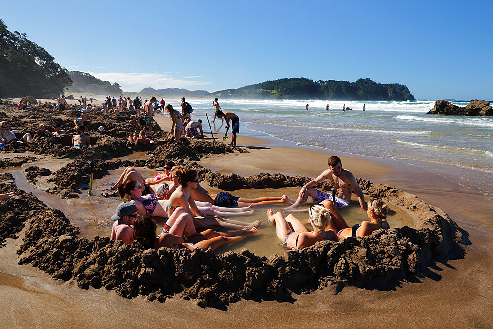 Tourists relaxing in hot pools dug on beach, Hot Water Beach, Coromandel Peninsula, Waikato, North Island, New Zealand, Pacific