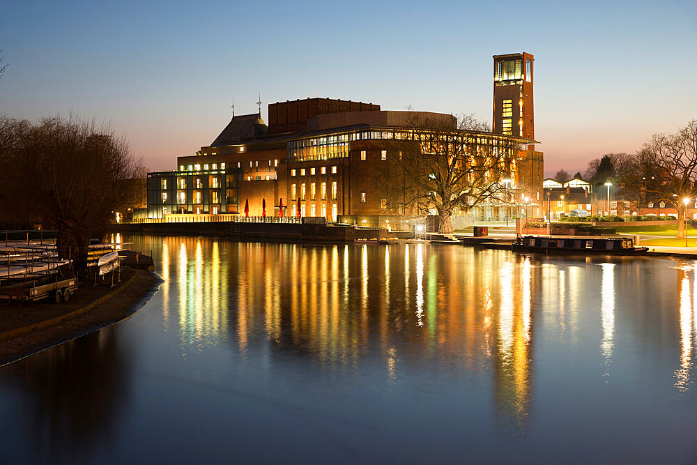 Royal Shakespeare Theatre lit up at dusk beside River Avon, Stratford-upon-Avon, Warwickshire, England, United Kingdom, Europe