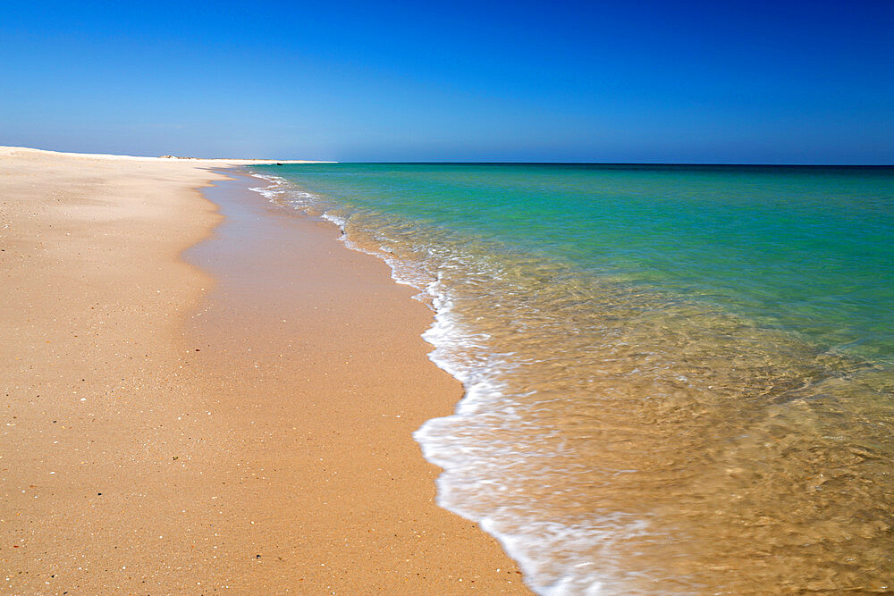 Empty white sand beach and breaking waves of crystal clear sea, Ilha do Farol, Culatra barrier island, Olhao, Algarve, Portugal, Europe