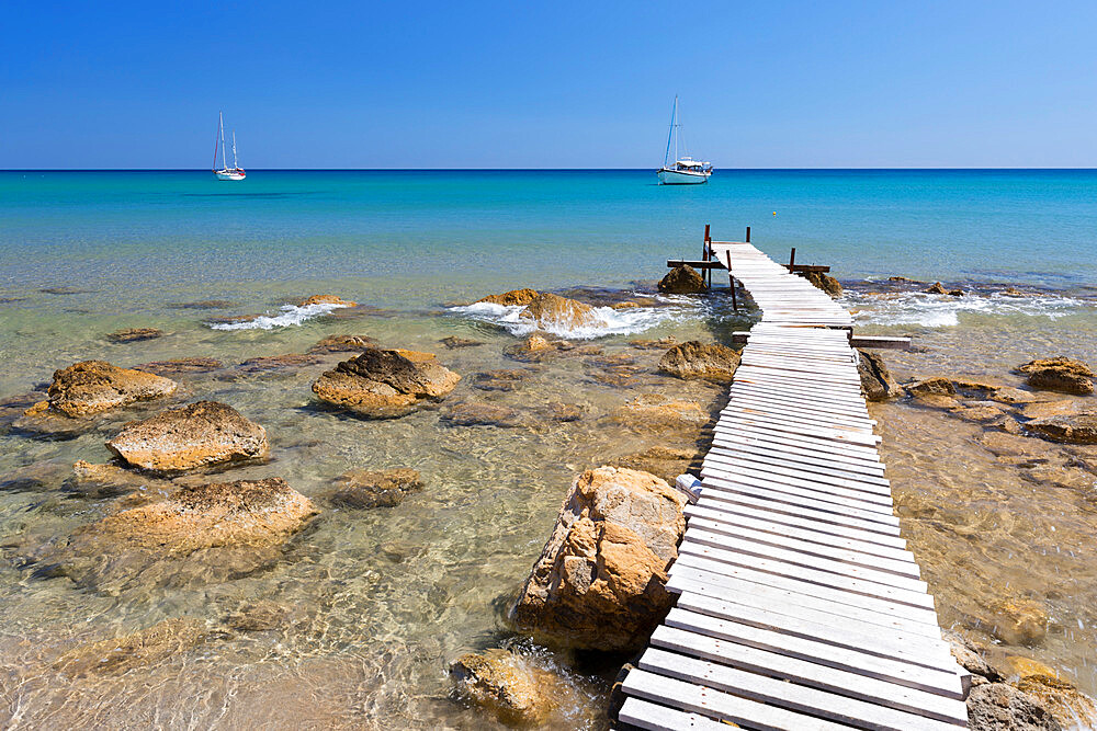 Wooden pier and clear turquoise sea with yachts at Provatas beach, Milos, Cyclades, Aegean Sea, Greek Islands, Greece, Europe