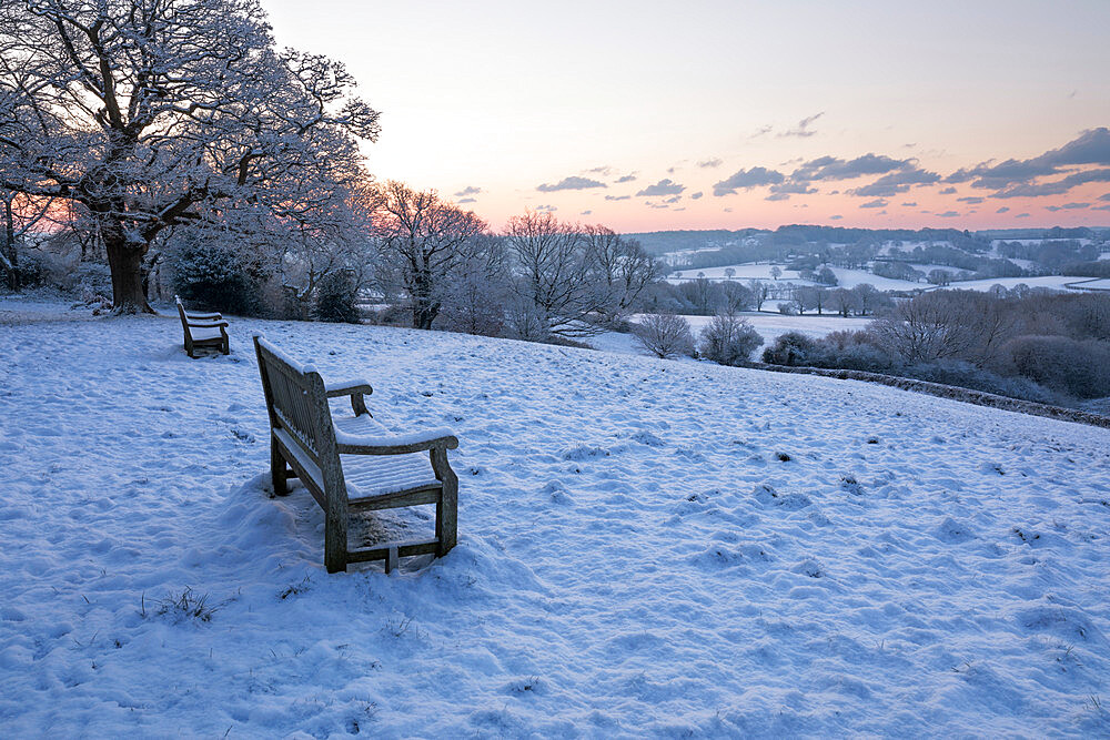 Bench overlooking snow covered High Weald landscape at sunrise, Burwash, East Sussex, England, United Kingdom, Europe