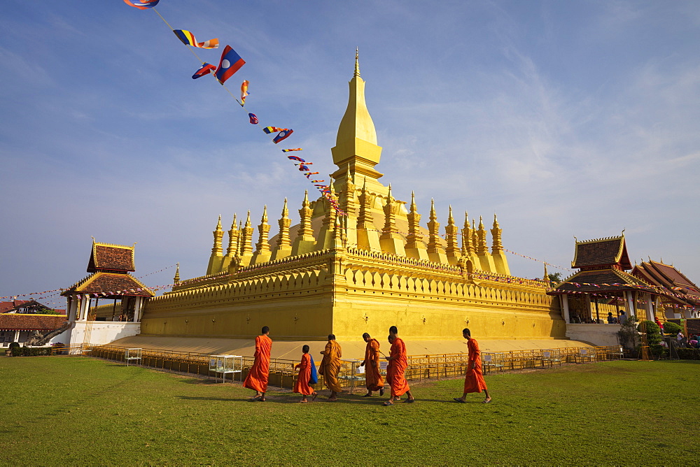 The golden Buddhist stupa of Pha That Luang with Buddhist monks walking below, Vientiane, Laos, Indochina, Southeast Asia, Asia