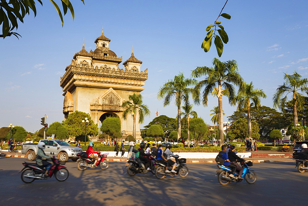 Mopeds riding past the Patuxai Victory Monument (Vientiane Arc de Triomphe), Vientiane, Laos, Indochina, Southeast Asia, Asia