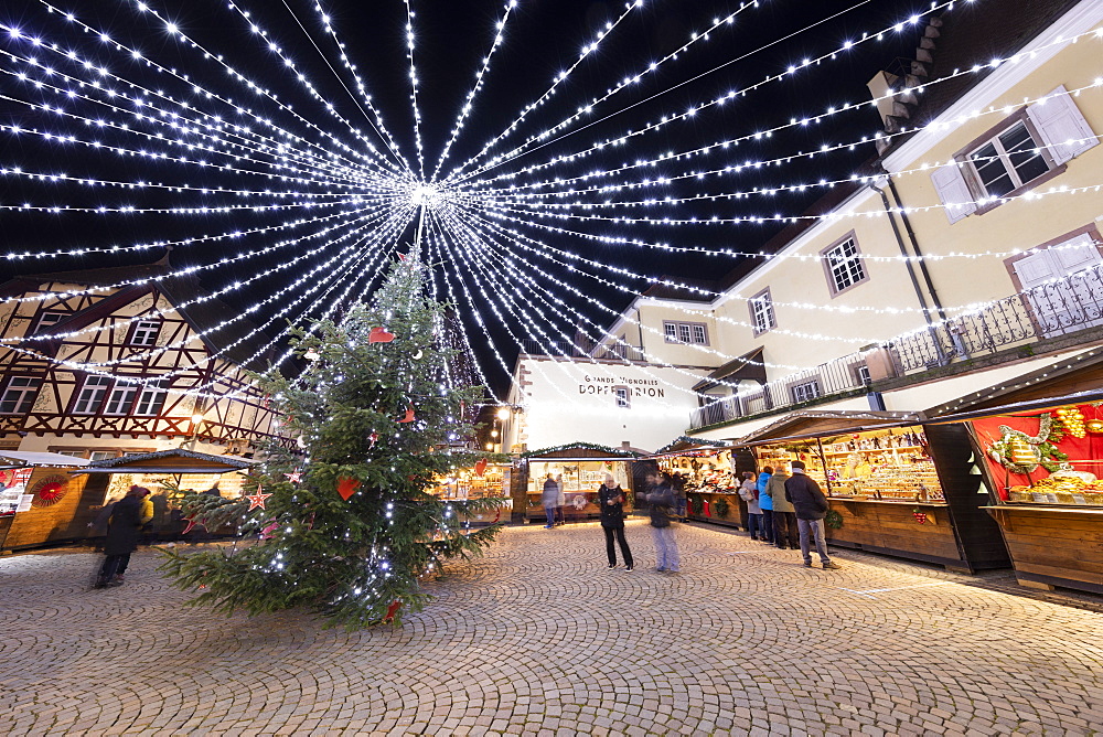 Christmas market with stalls illuminated at night at the Place Fernand Zeyer, Riquewihr, Alsace, France, Europe